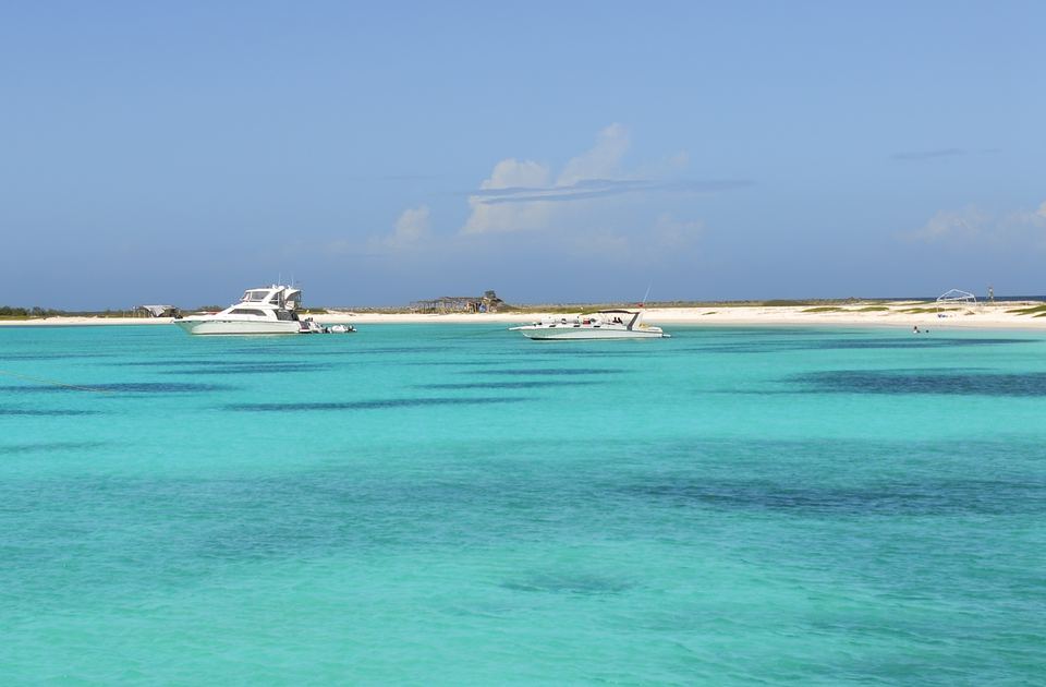 Boats at anchor off a white-sand beach on La Tortuga